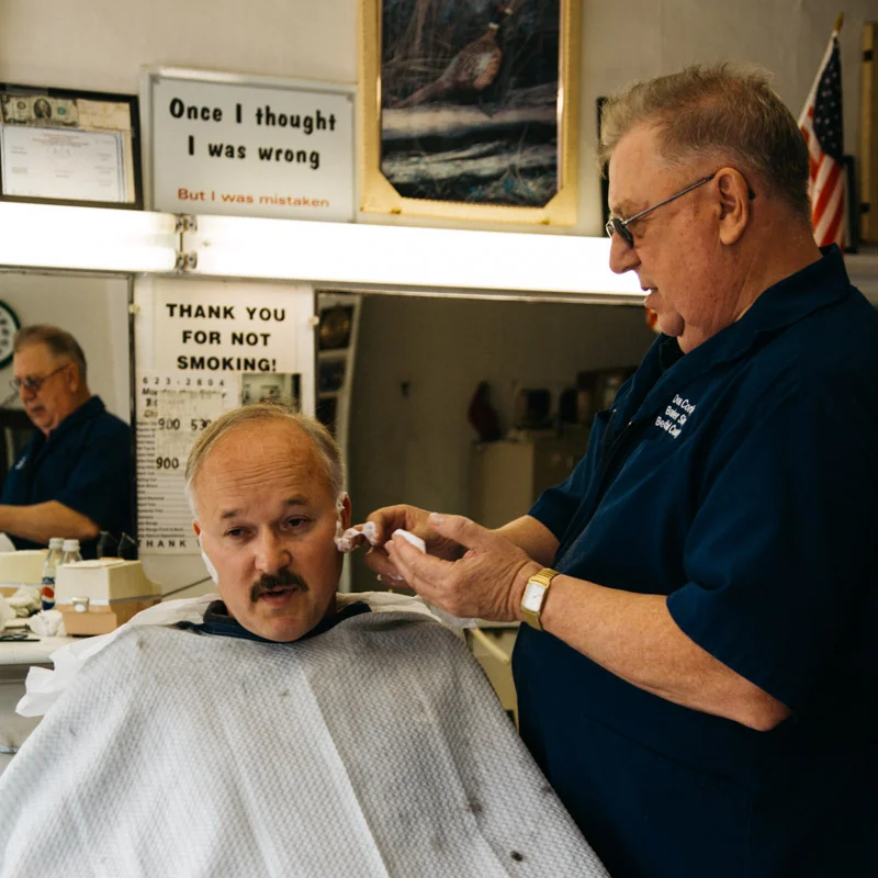 The barber at work on a customer in a white cape