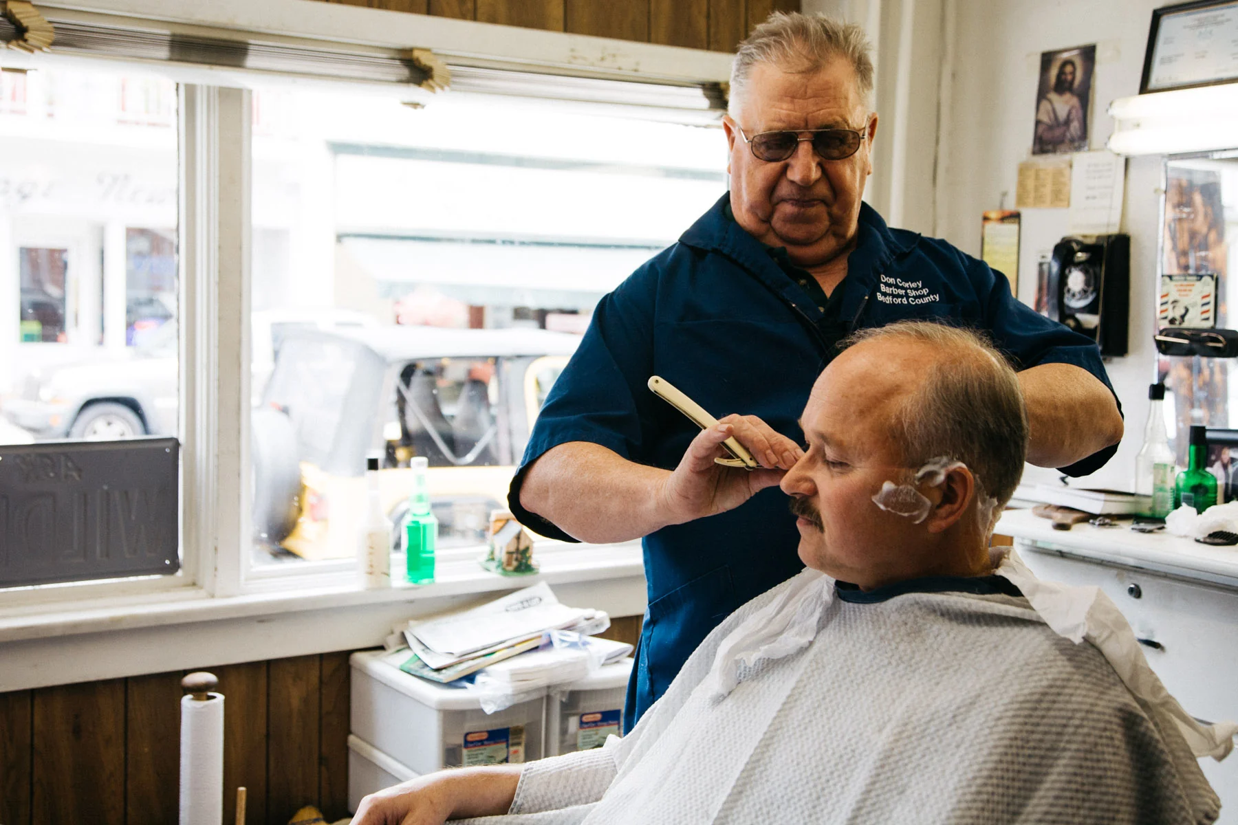 The barber trimming a customer's moustache inside the shop