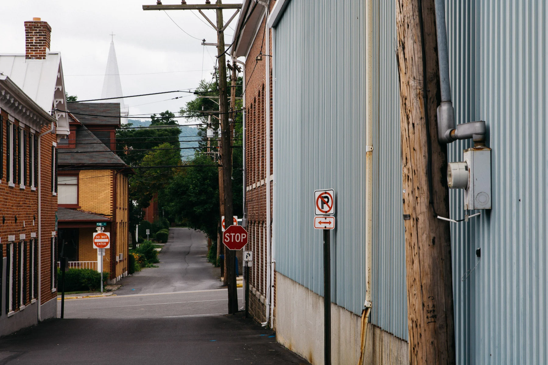 A quiet side street between clapboard buildings and a church spire