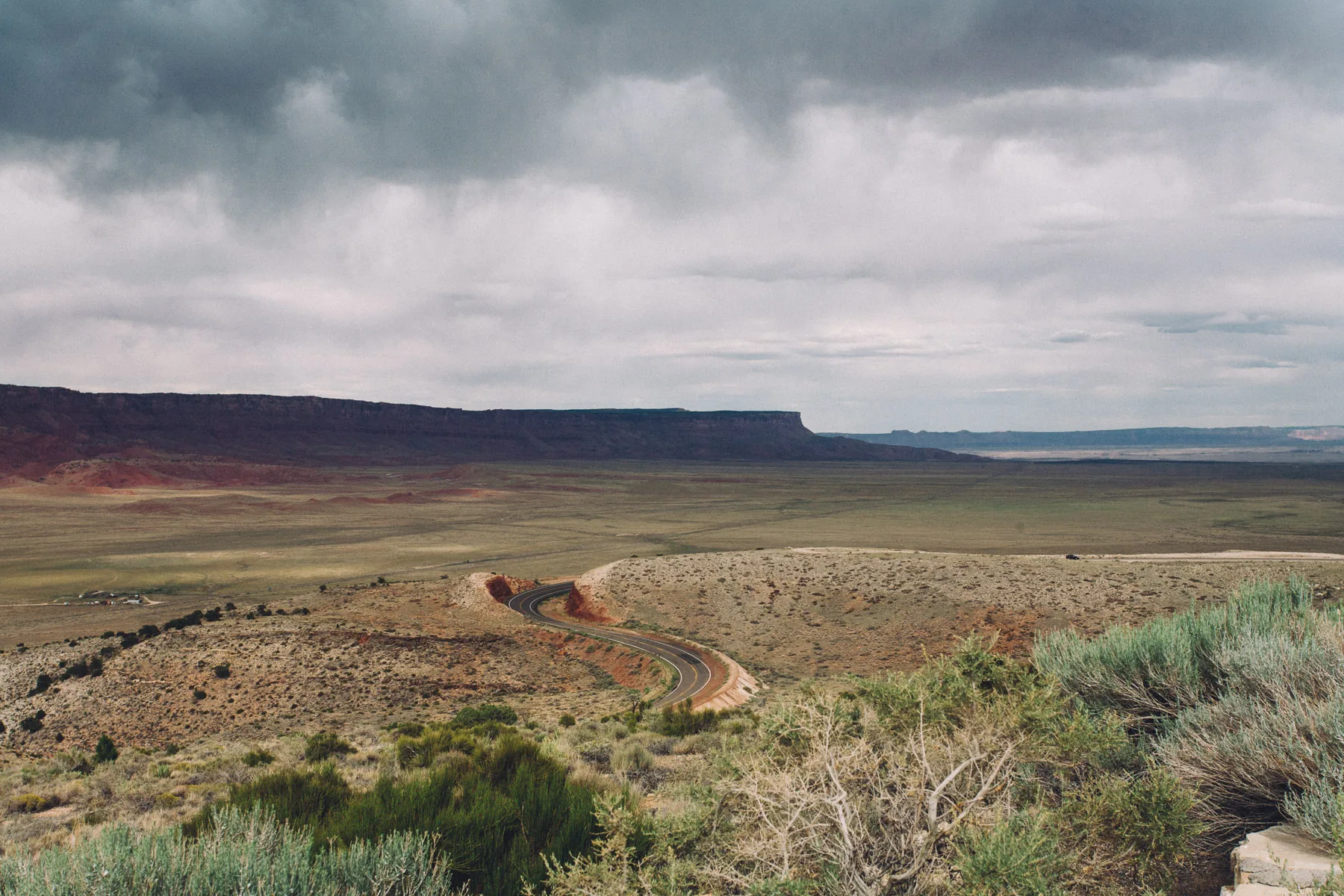 The road winding down toward the Vermilion Cliffs under storm clouds