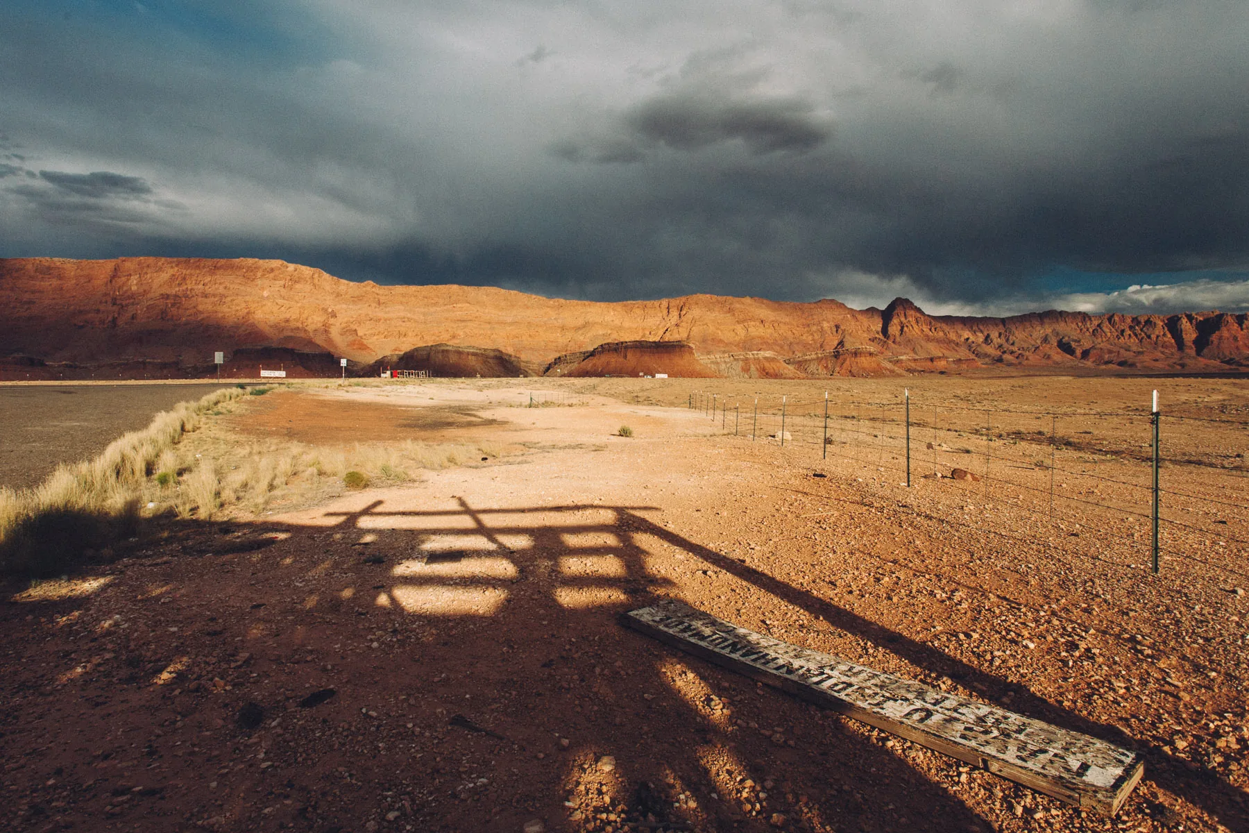 Long shadows of a fence across the sand near the cliffs