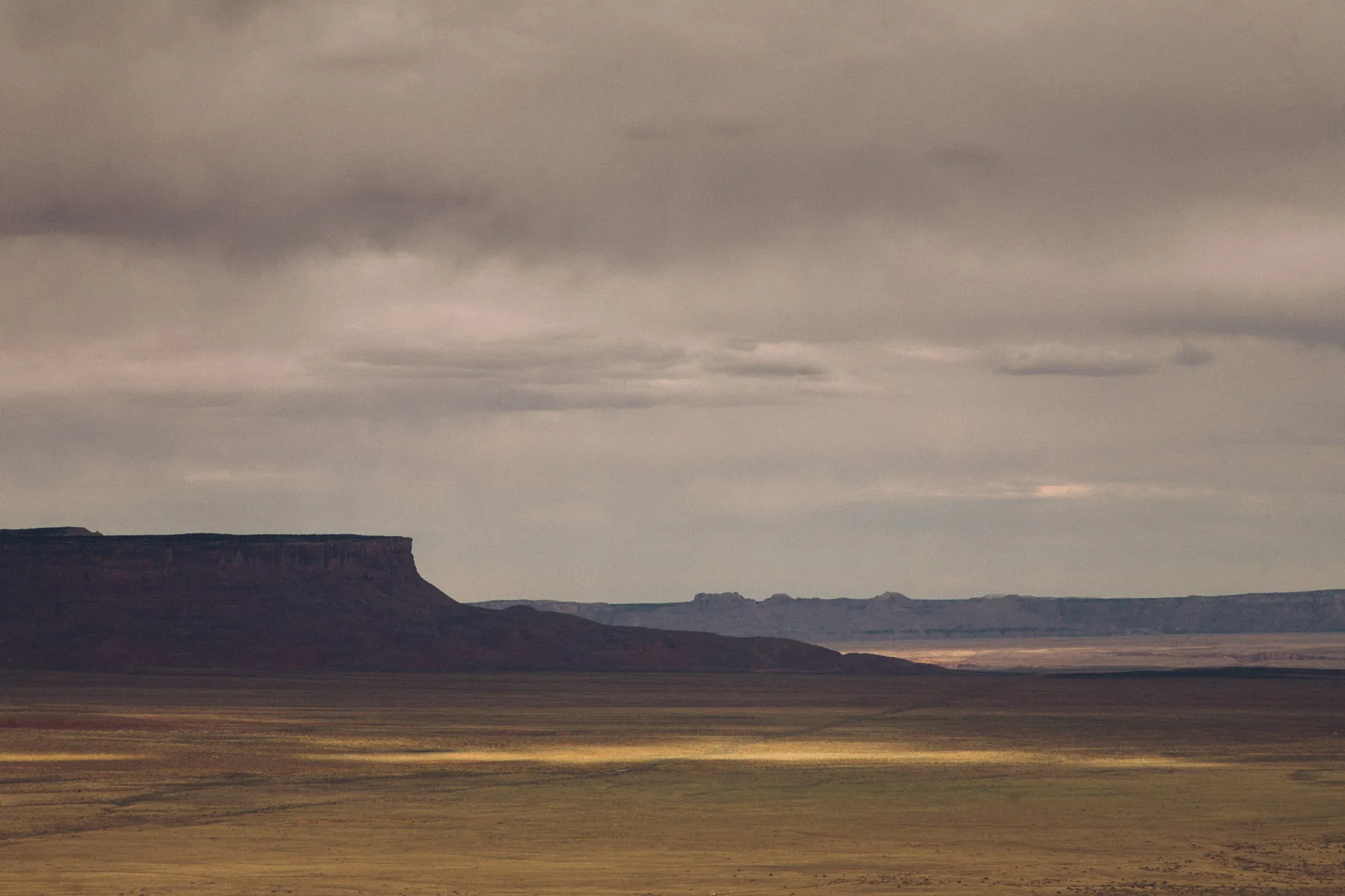 A distant mesa under a soft pink and grey sky
