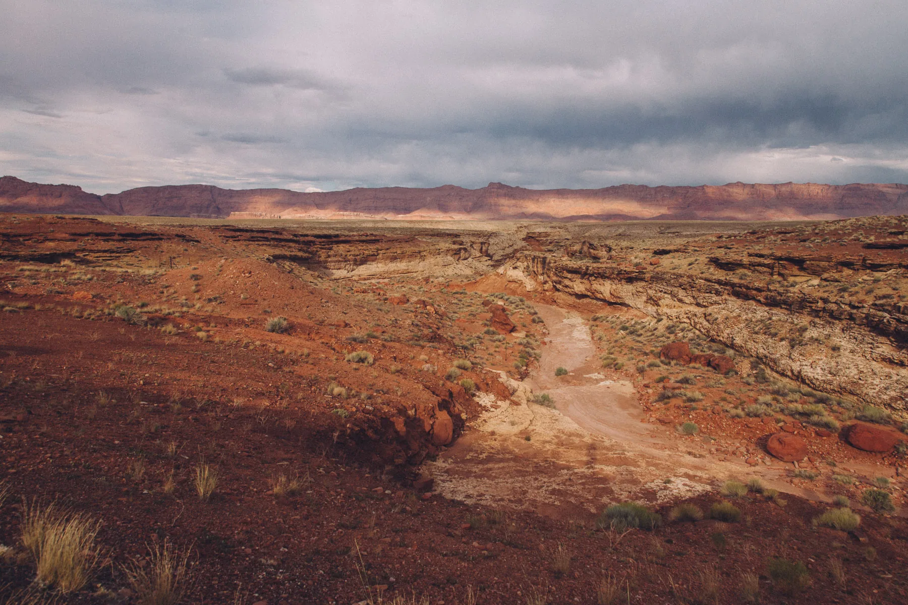 A dirt track crossing the red desert toward the cliffs