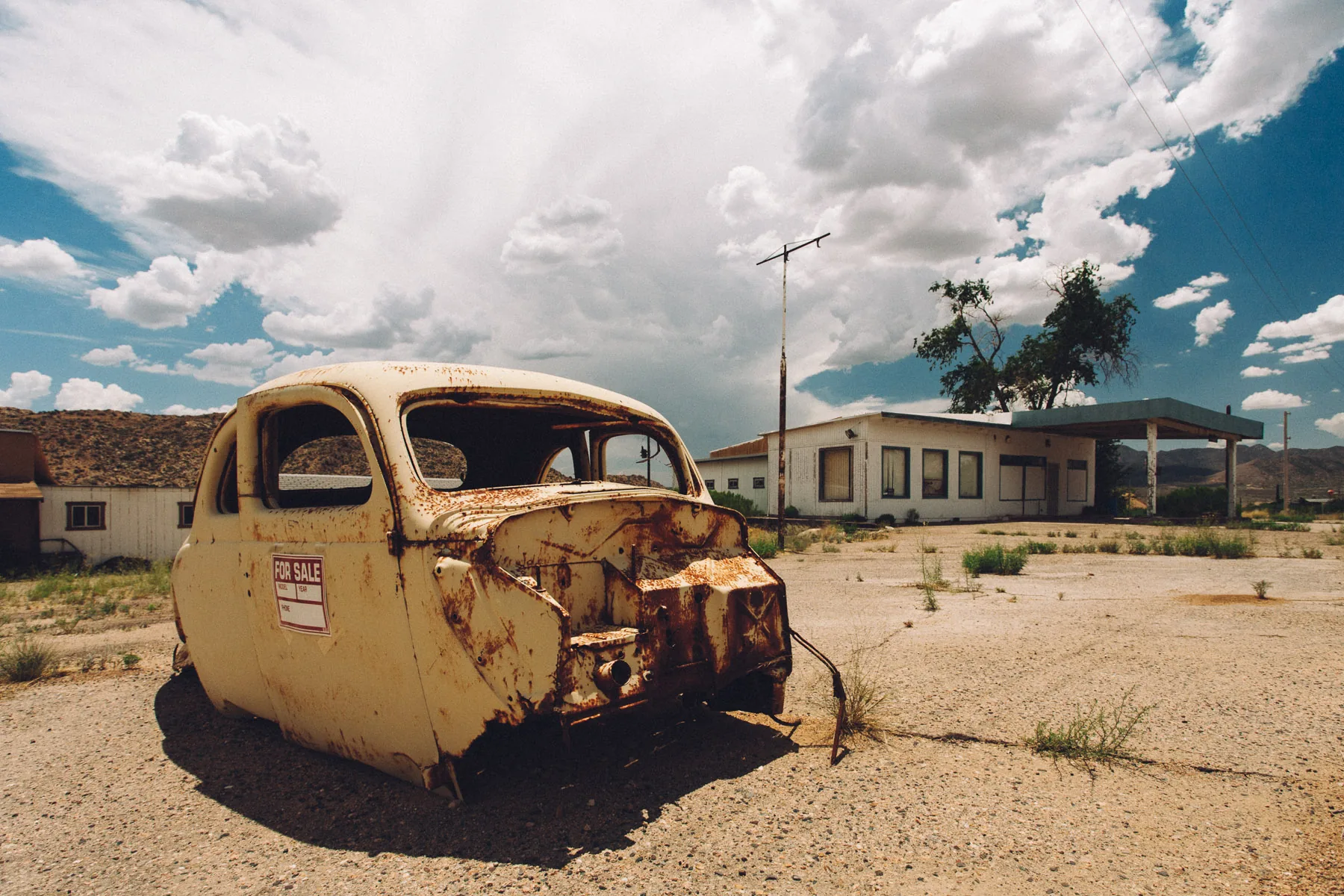 A rusted yellow car body in the desert