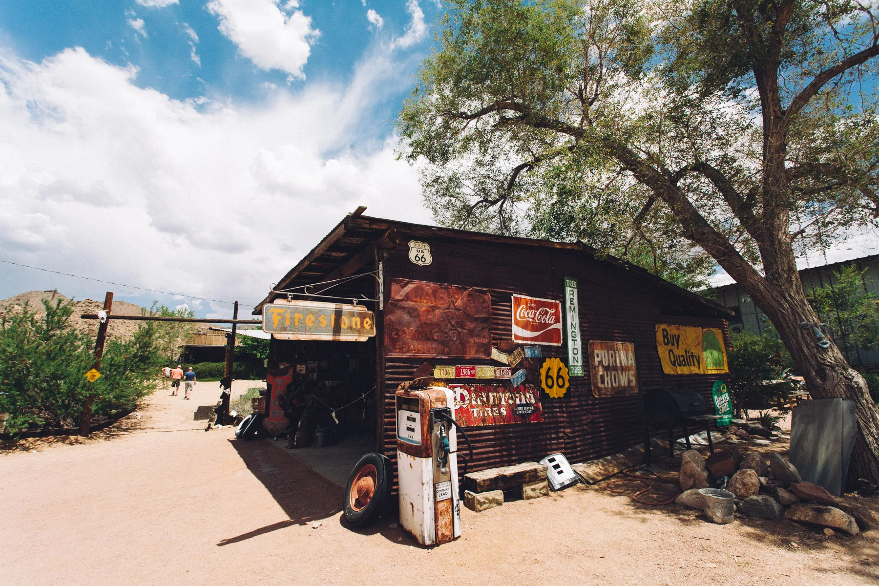 Old signs and a vintage pump outside a rusty shed in Hackberry