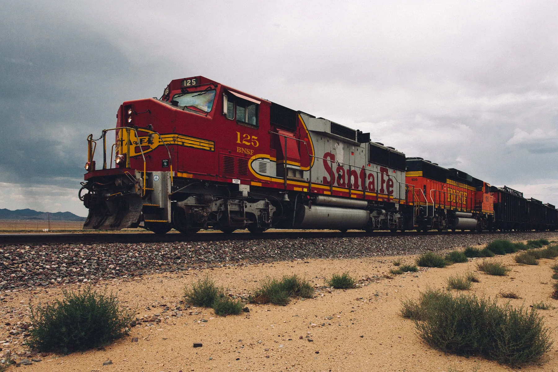 A red and silver Santa Fe locomotive leading a freight train
