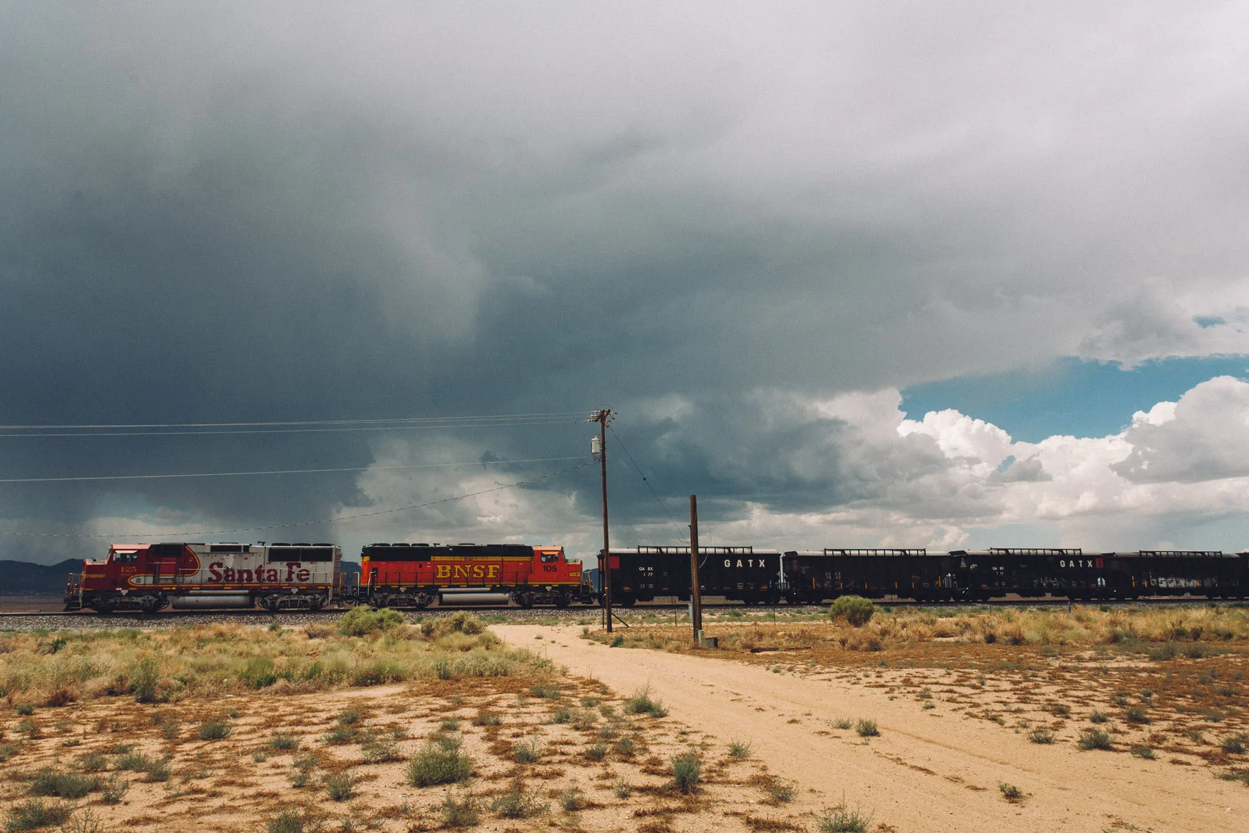 BNSF and Santa Fe locomotives pulling a train under a storm sky