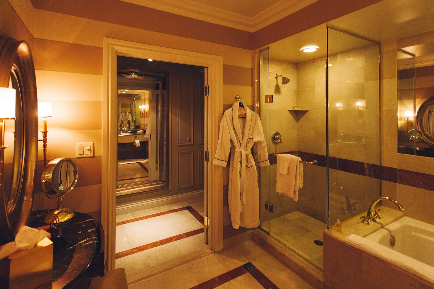 The marble bathroom with a bathrobe, glass shower and tub