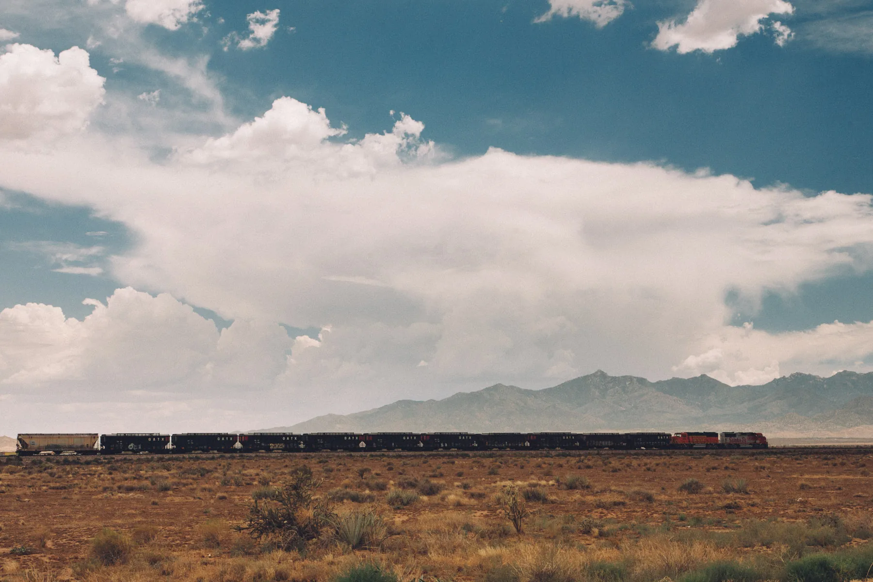 A long freight train crossing the desert below the mountains