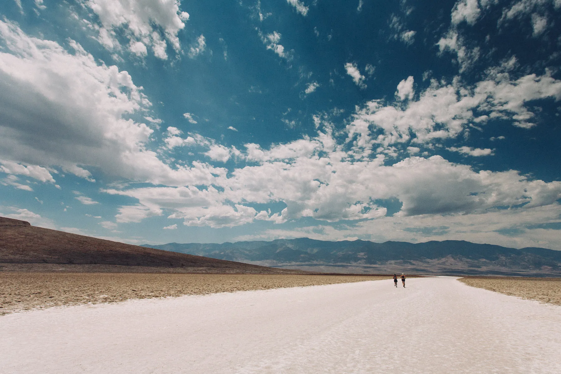 Two people walking out on the white salt flat at Badwater Basin