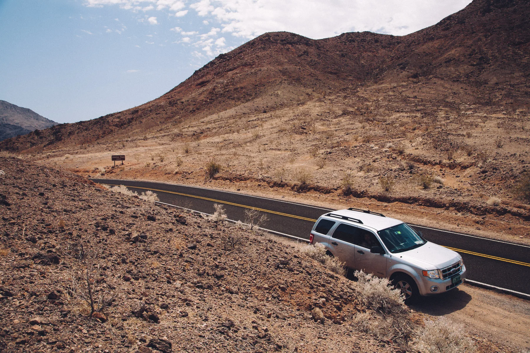 Our car parked by the road below a brown mountain
