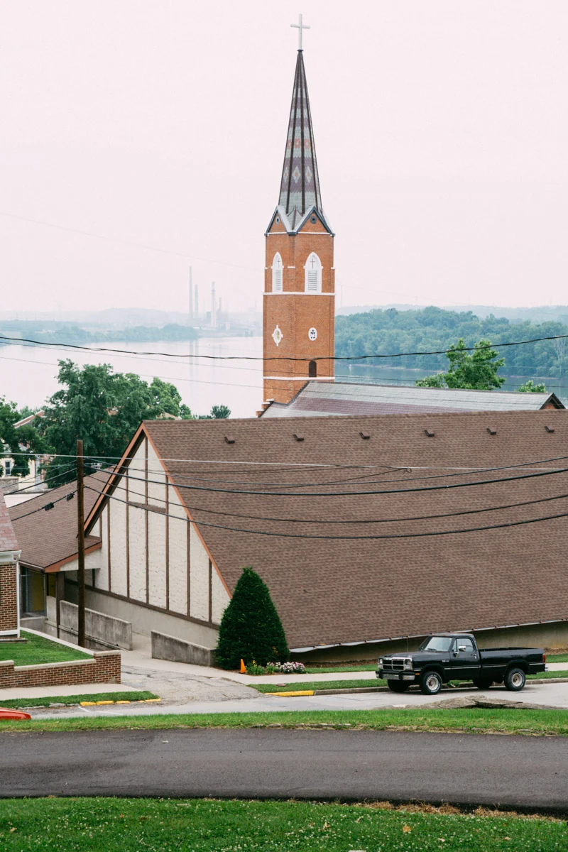 A church spire above rooftops by the Ohio River