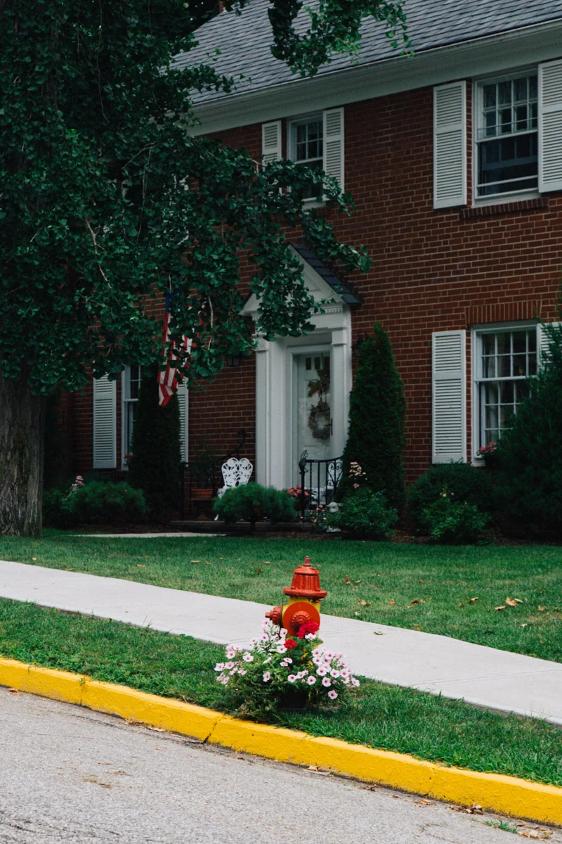 A brick house with a flower bed and a red fire hydrant