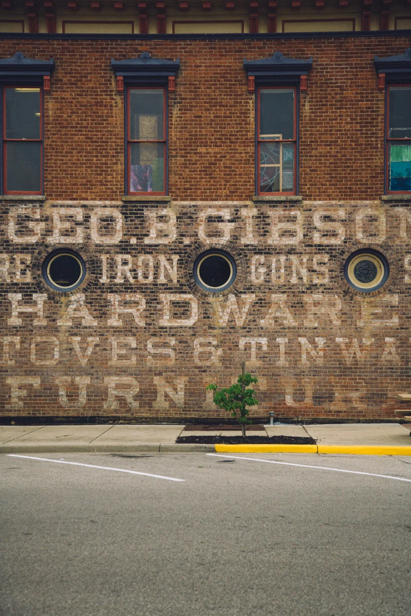 An old painted hardware advertisement on a brick wall