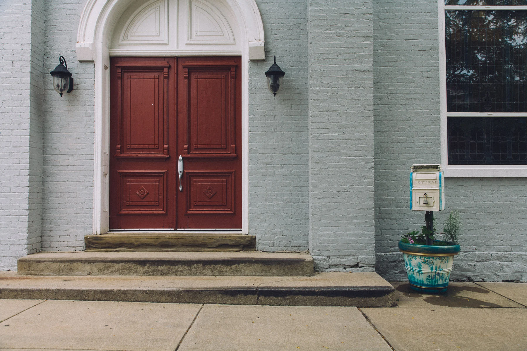 A red double door in a pale grey brick church