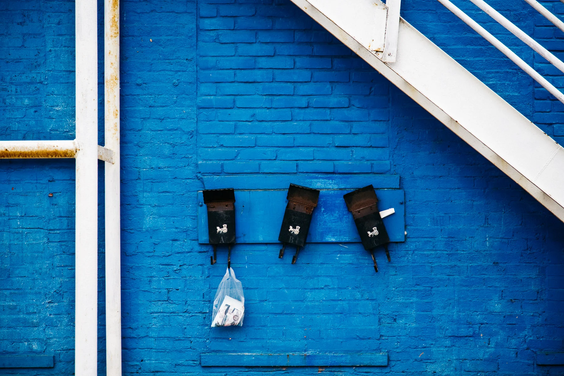A deep blue brick wall under a white metal staircase