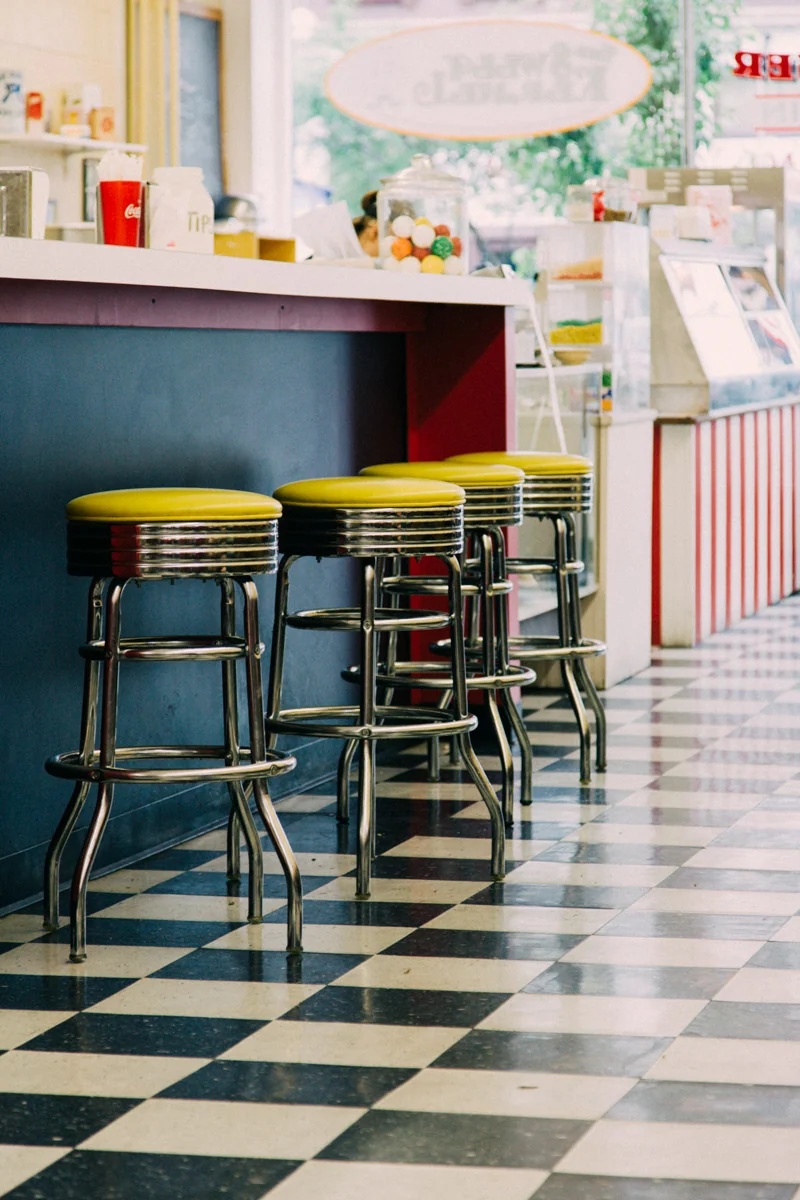 Red diner stools along a counter over a checkerboard floor