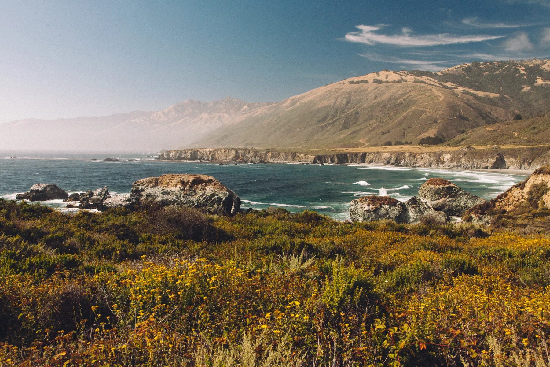Golden scrub above the coast and the distant mountains