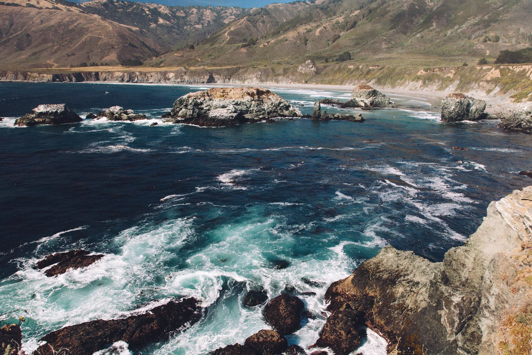 Turquoise water swirling around the rocks of a bay