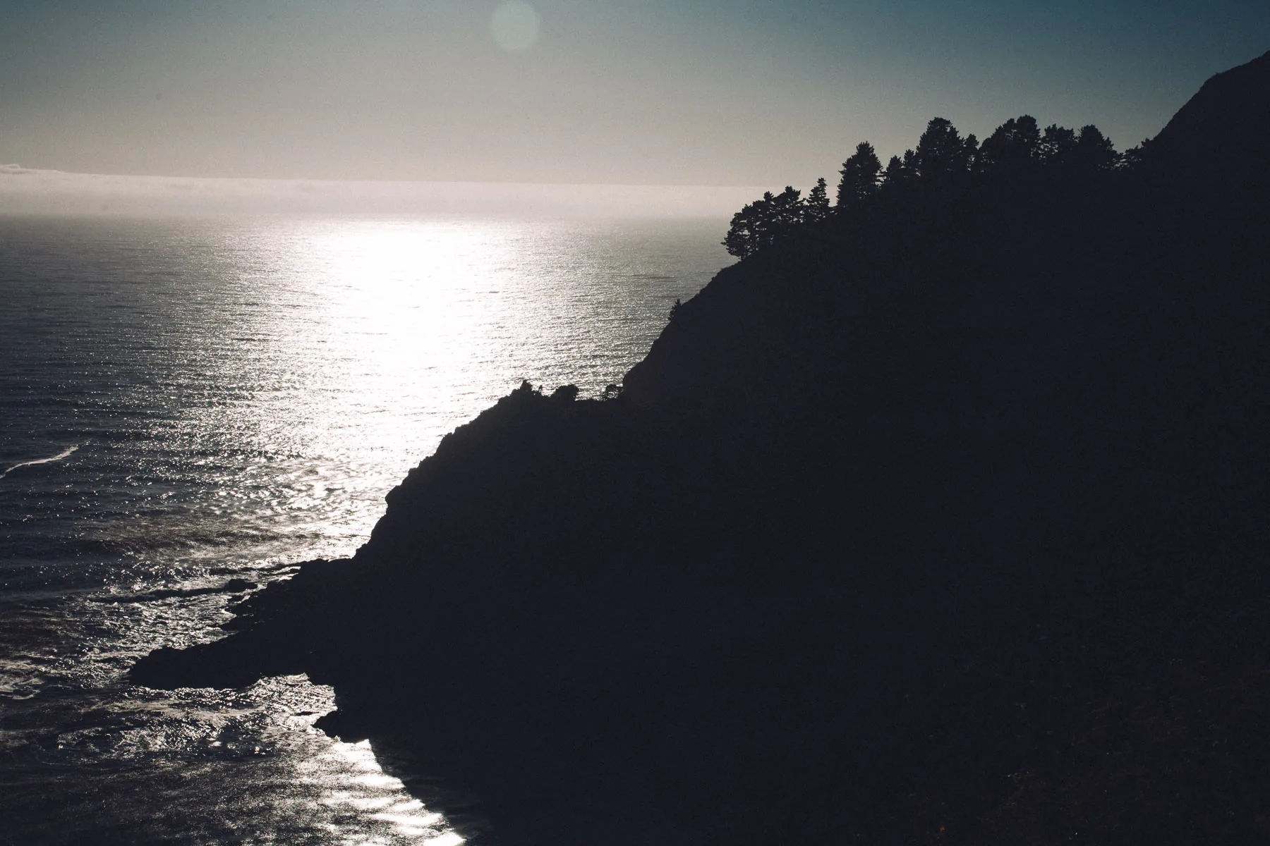 A dark headland silhouetted against the shining sea