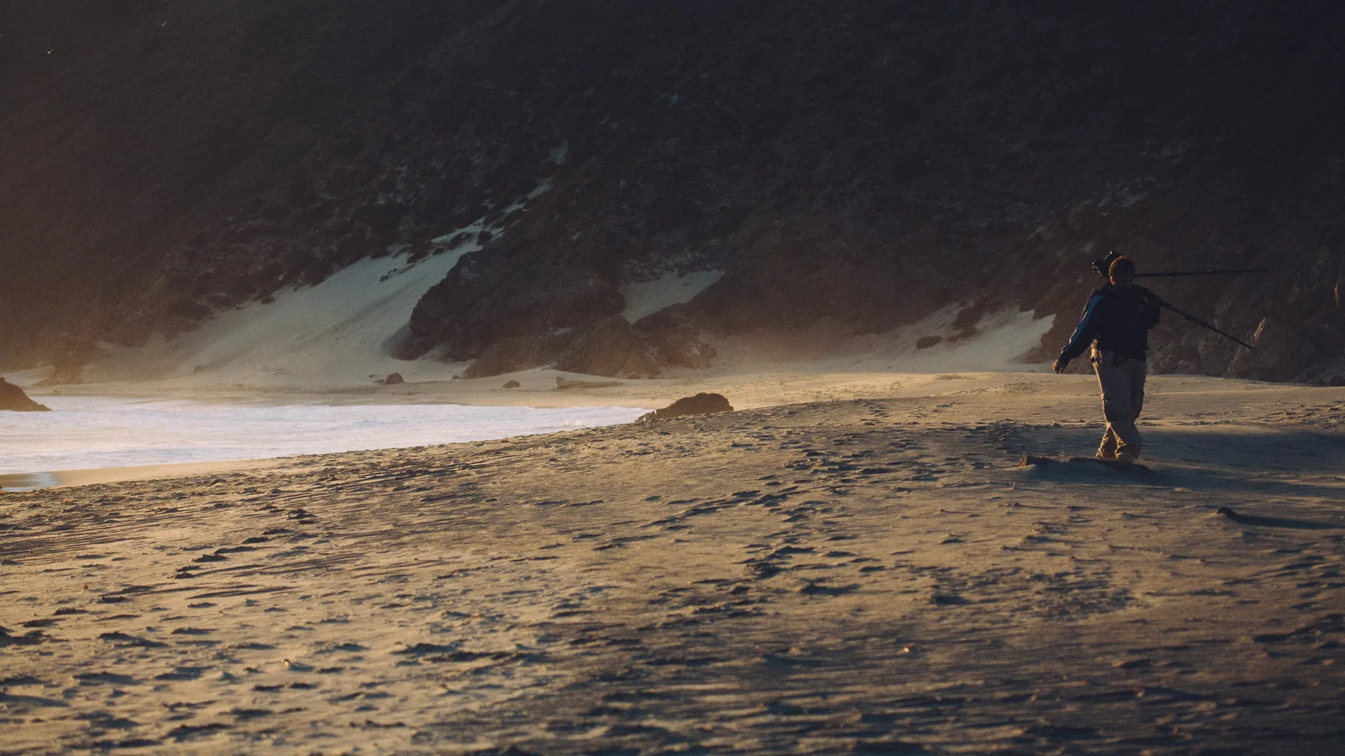 A man walking across the beach in the evening haze