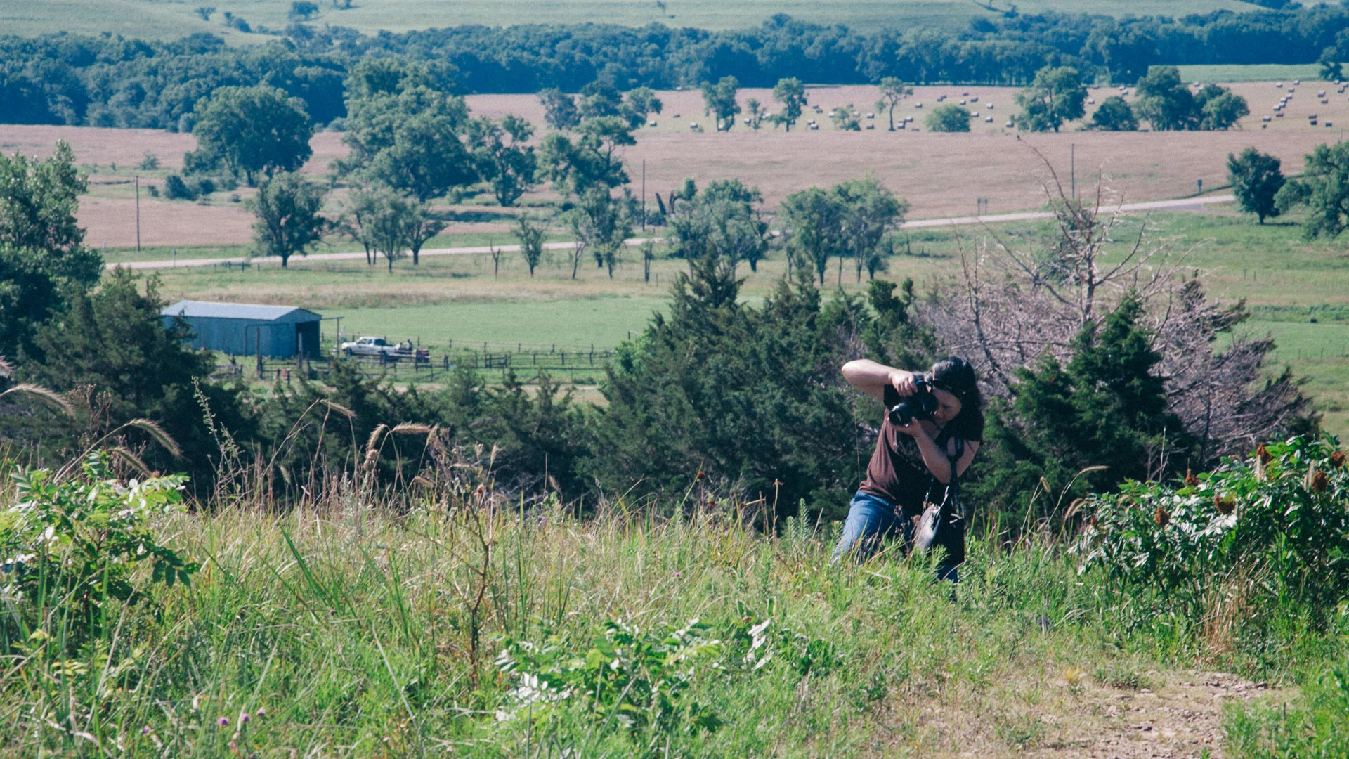 Francesco photographing from a hillside above farmland
