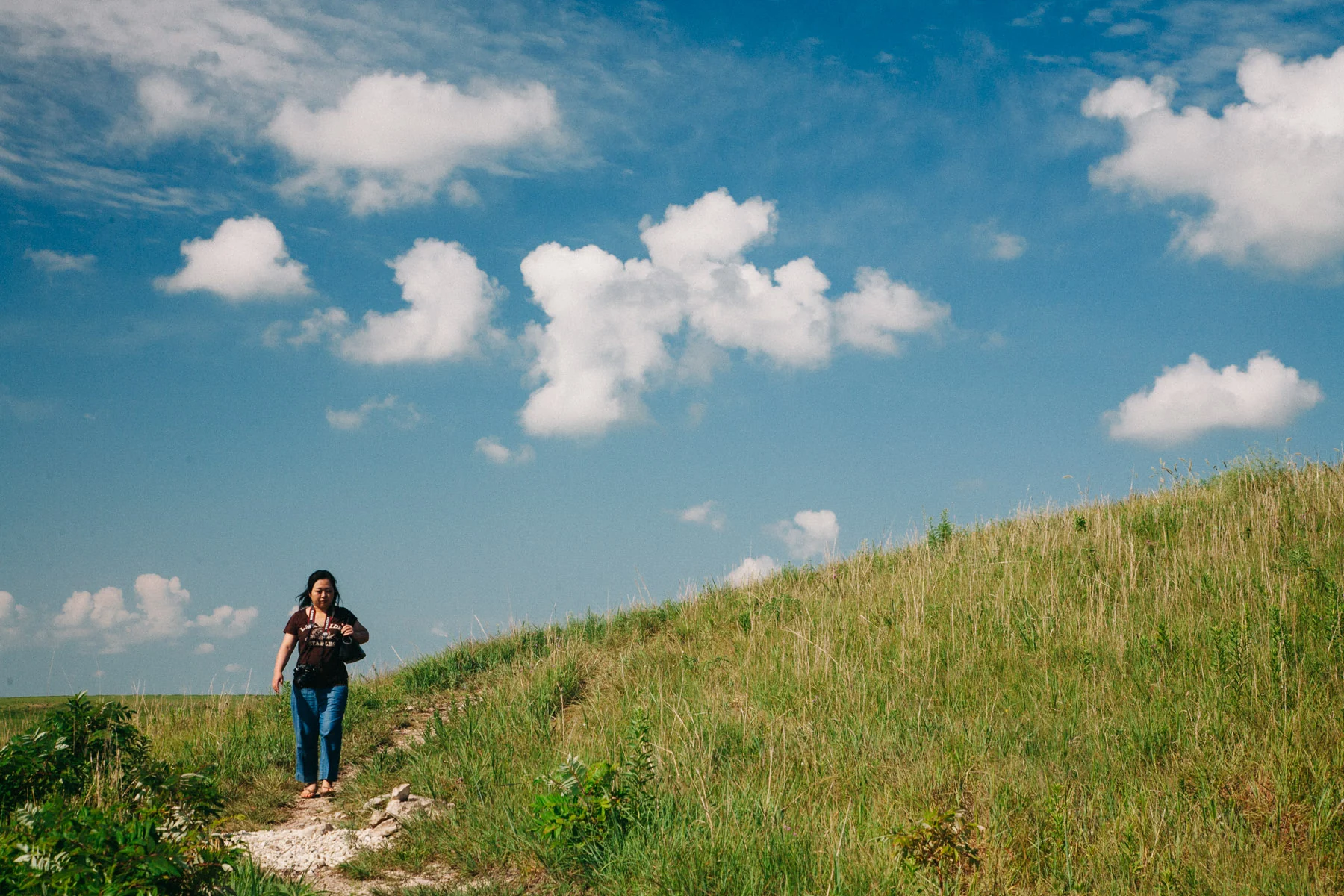 Yasuko walking along a prairie path under a blue sky