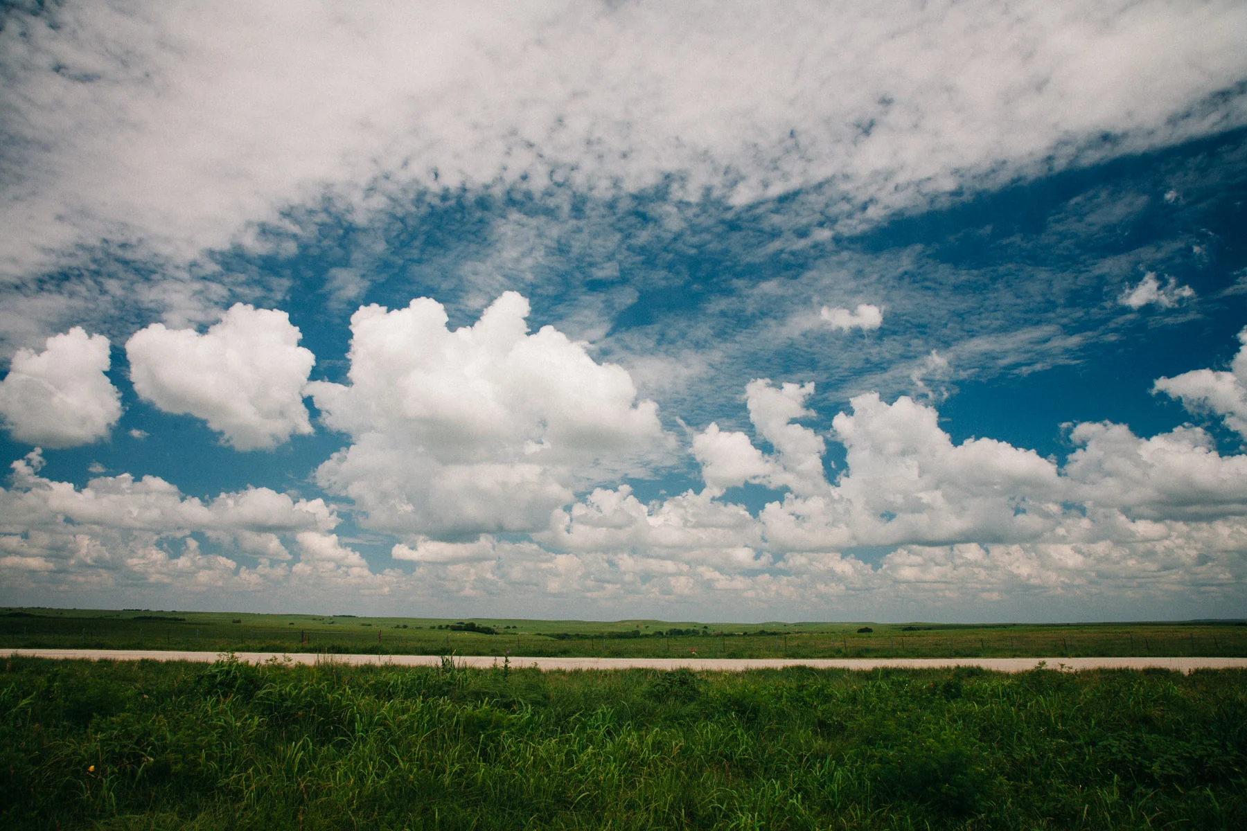 Clouds filling a vast sky over flat green plains