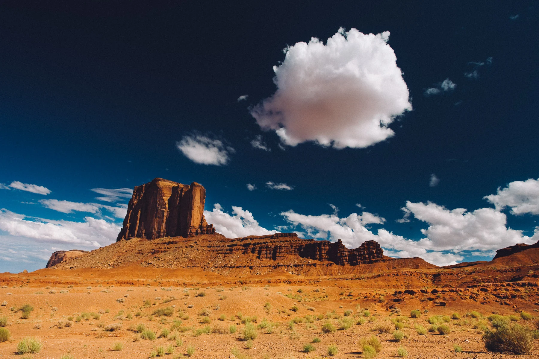 A single white cloud above a butte