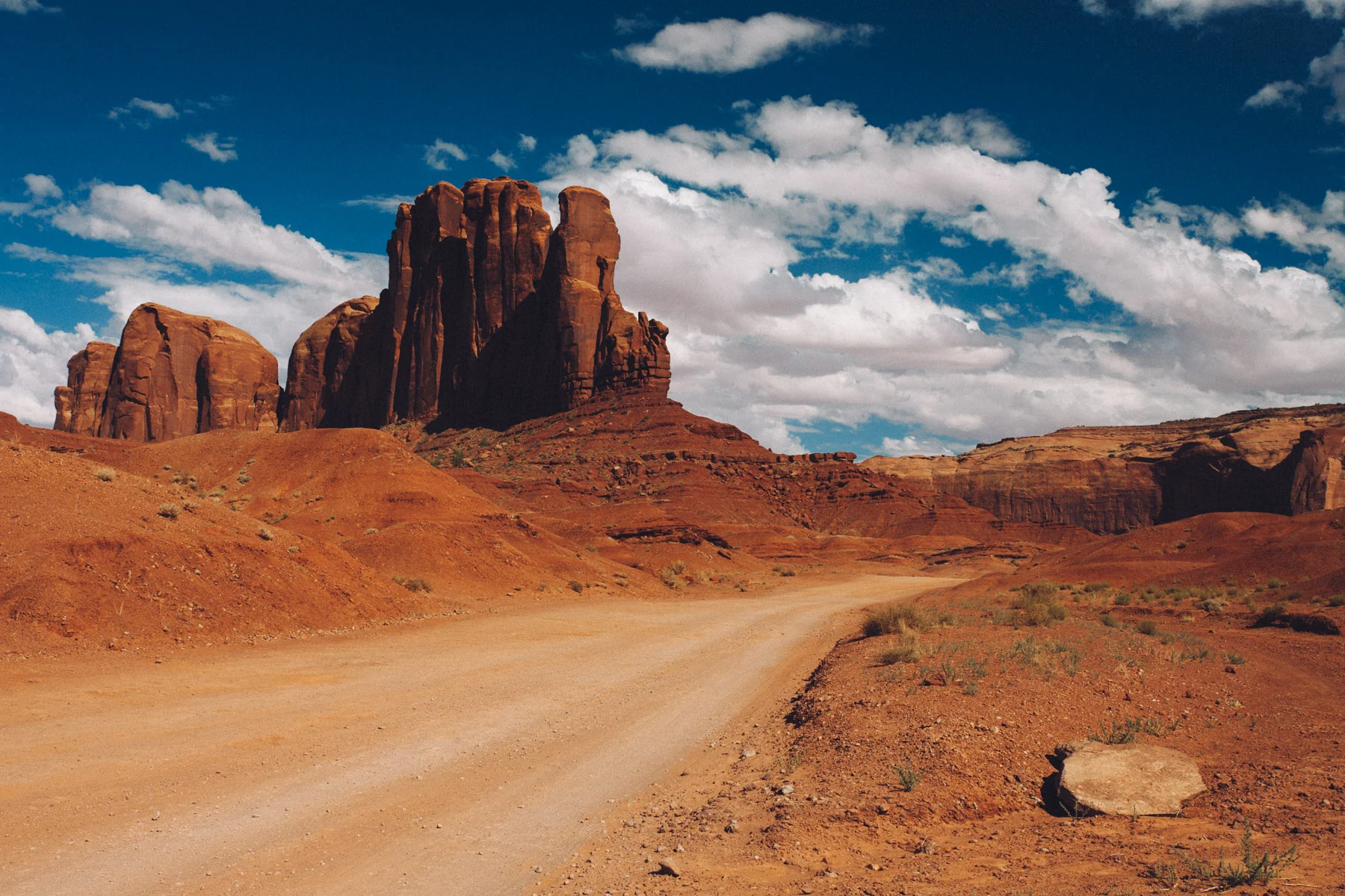 A dirt road curving towards red buttes