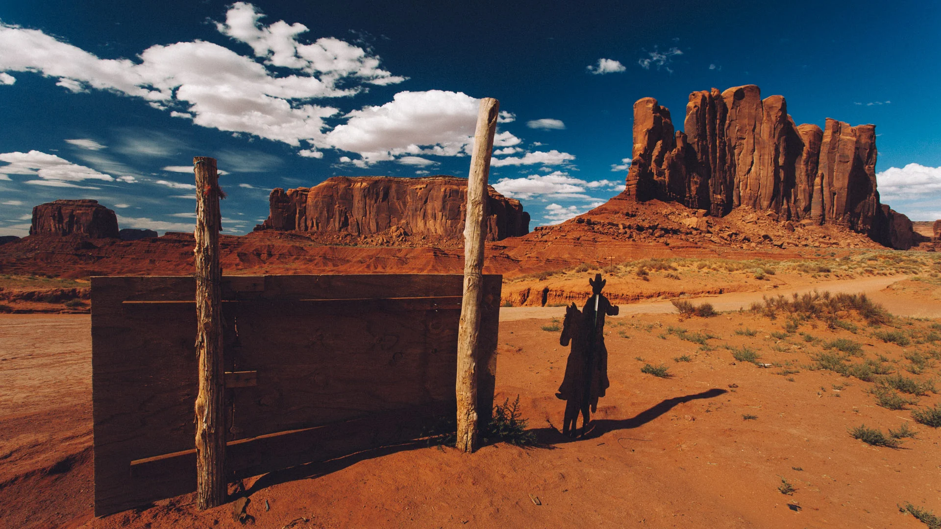 A wooden post and a figure in front of red buttes