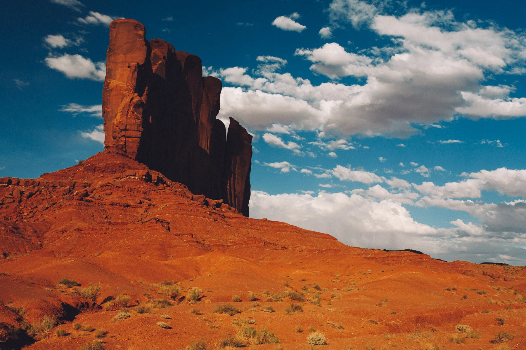 A tall rock formation above red sand