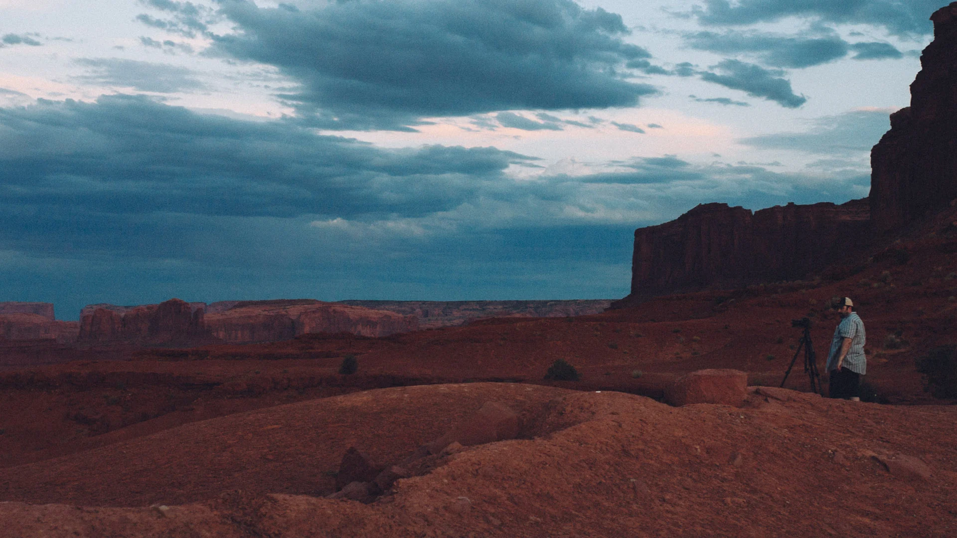 Francesco standing beneath a dark butte at dusk