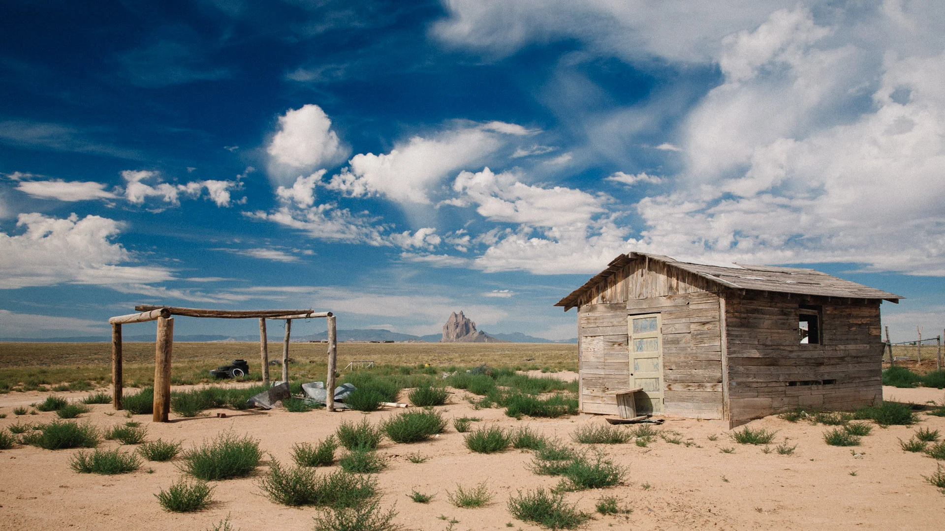 An abandoned shack and frame in the desert, with Shiprock on the horizon