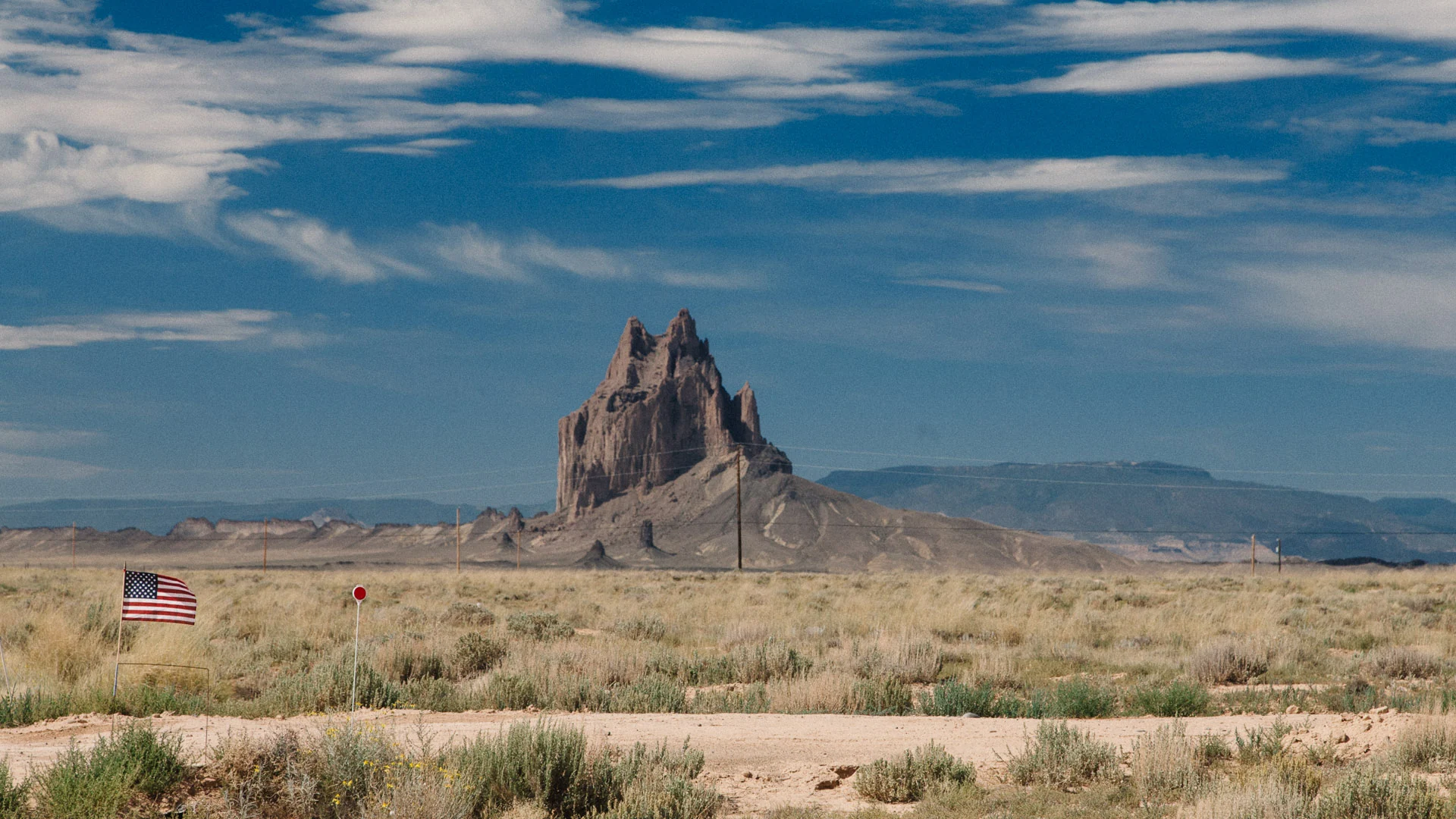 Shiprock beyond a flat desert plain