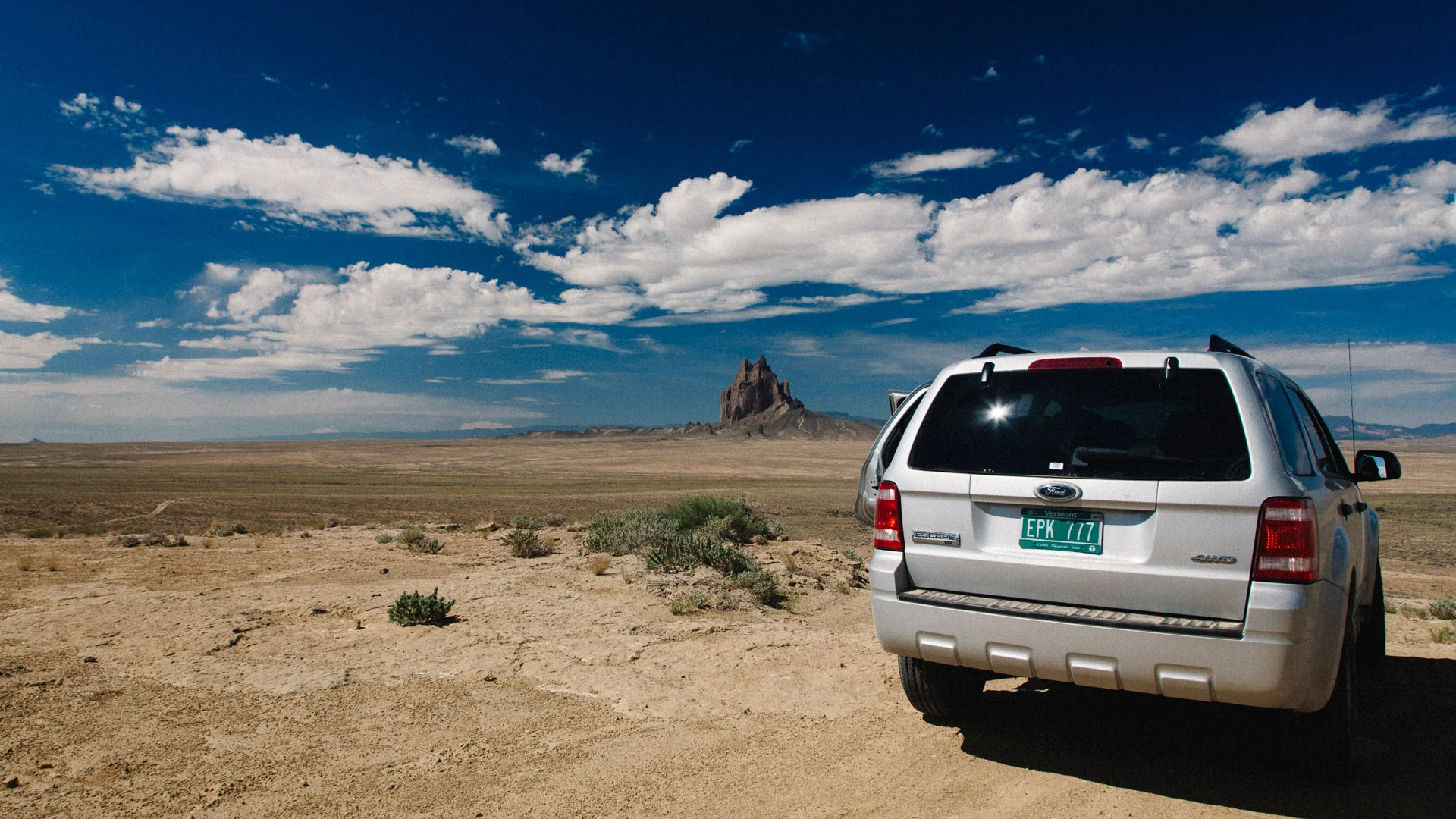 Our SUV parked on a dirt track facing Shiprock