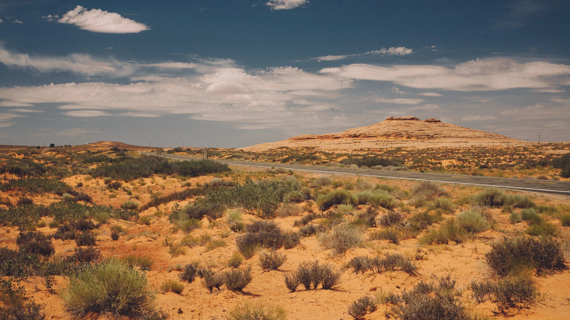 Desert scrub and a distant mesa under clouds