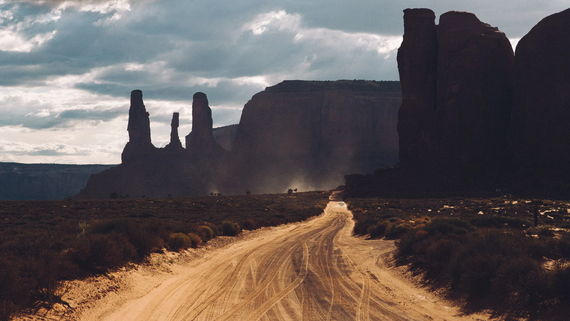 A dirt road leading through dark buttes towards the light