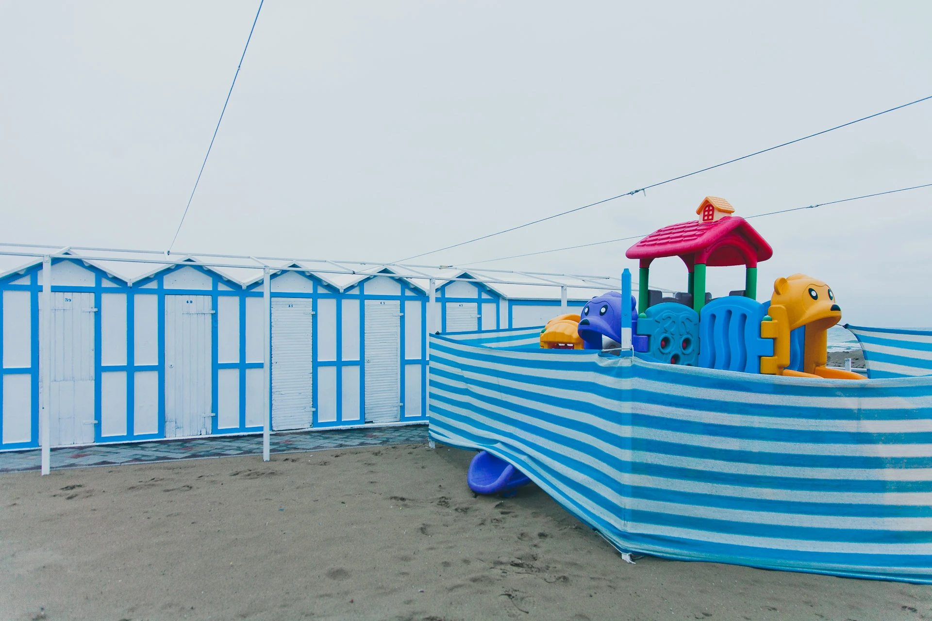 A colourful playground boat beside closed blue cabins