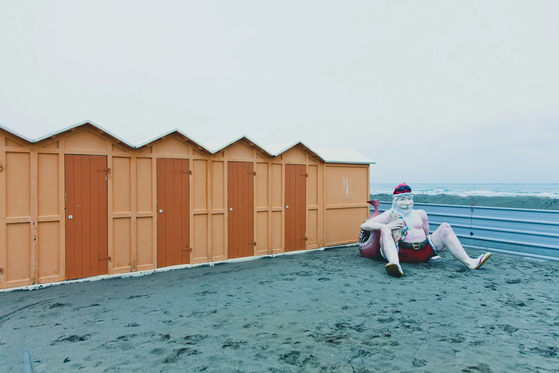 Beach cabins beside a seated cartoon figure sculpture