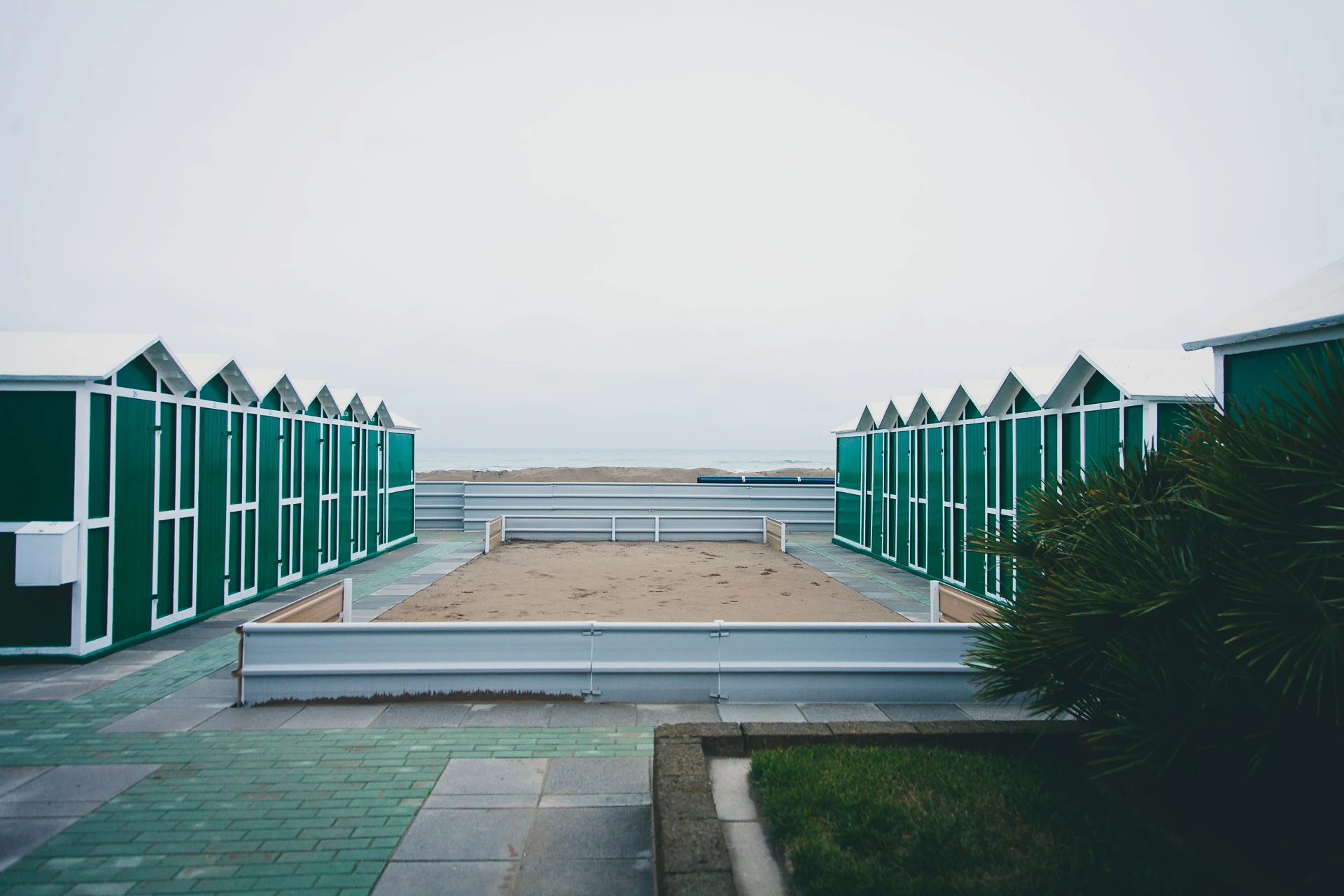 Green cabins framing a walkway toward the sea