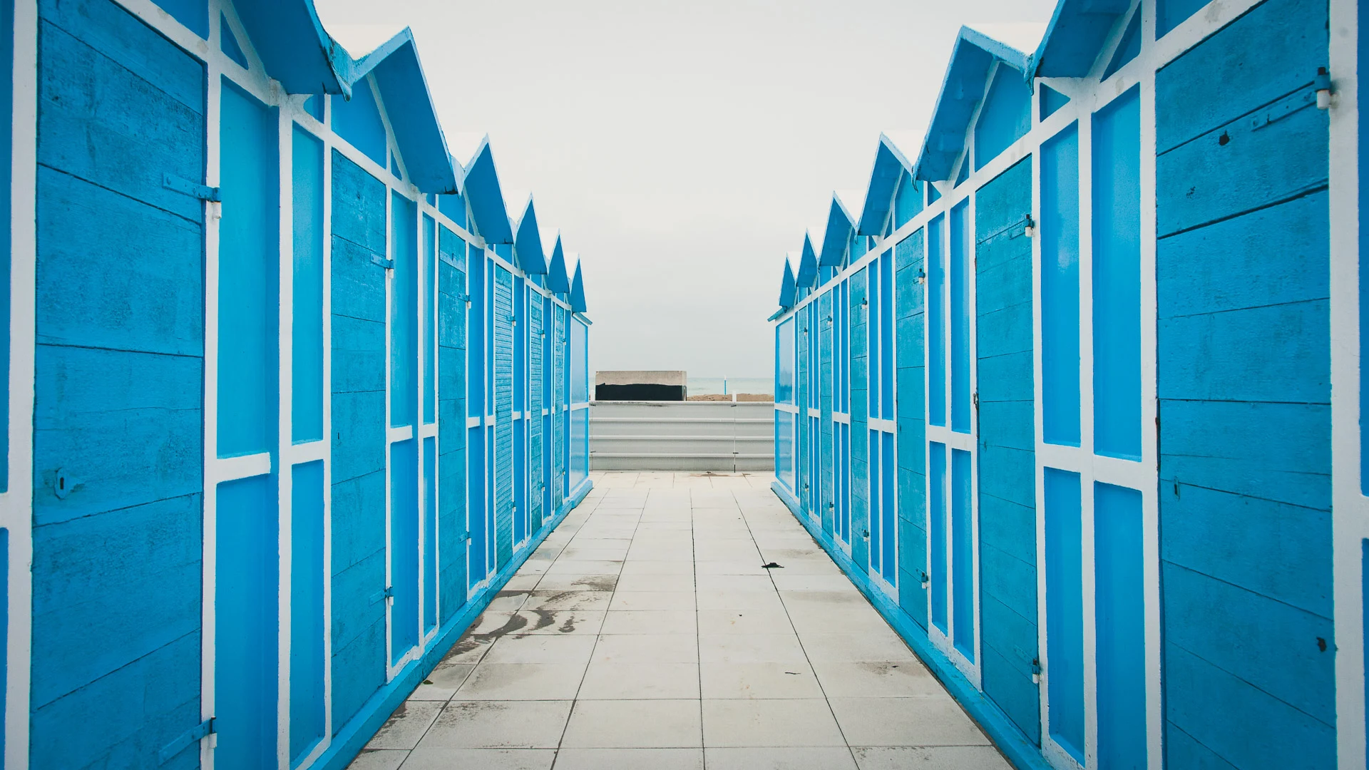 Rows of bright blue cabins opening toward the sea