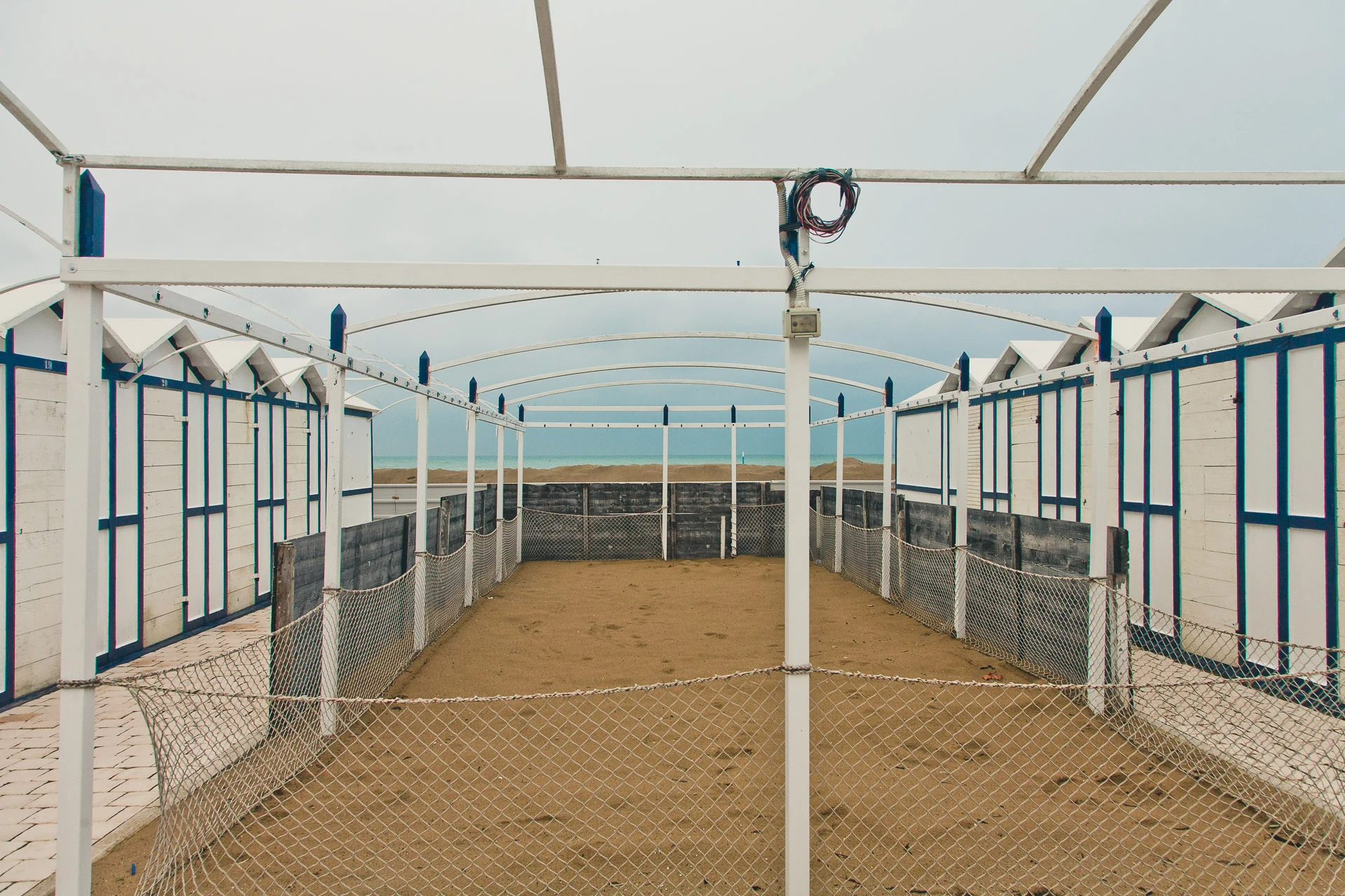 Bare canopy frame between closed beach cabins