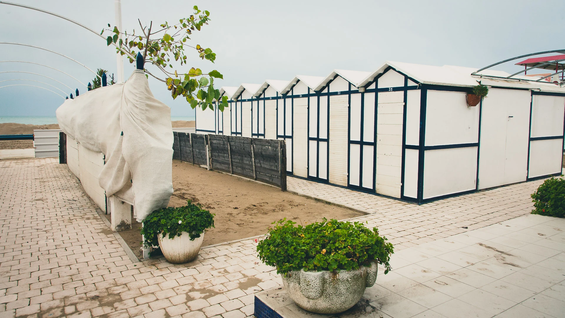 White elephant sculpture beside empty beach cabins