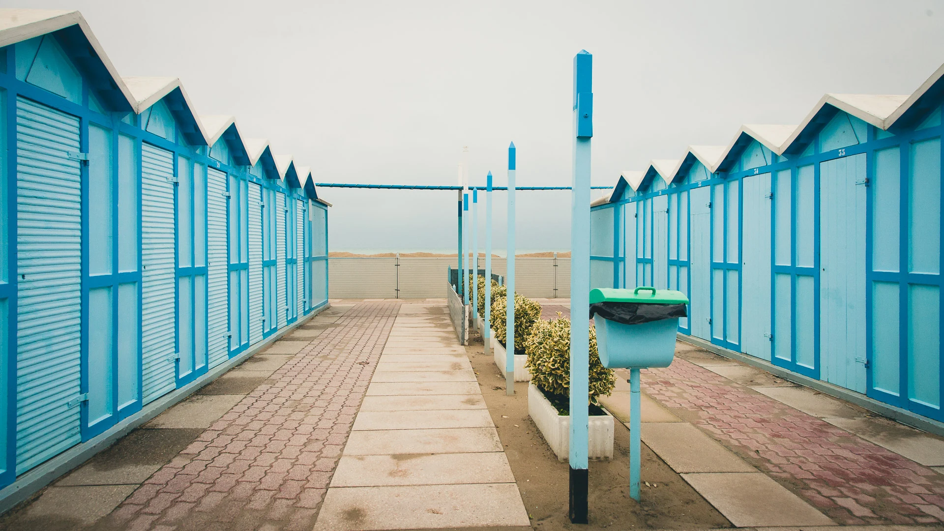 Blue cabins along a wooden walkway to the beach