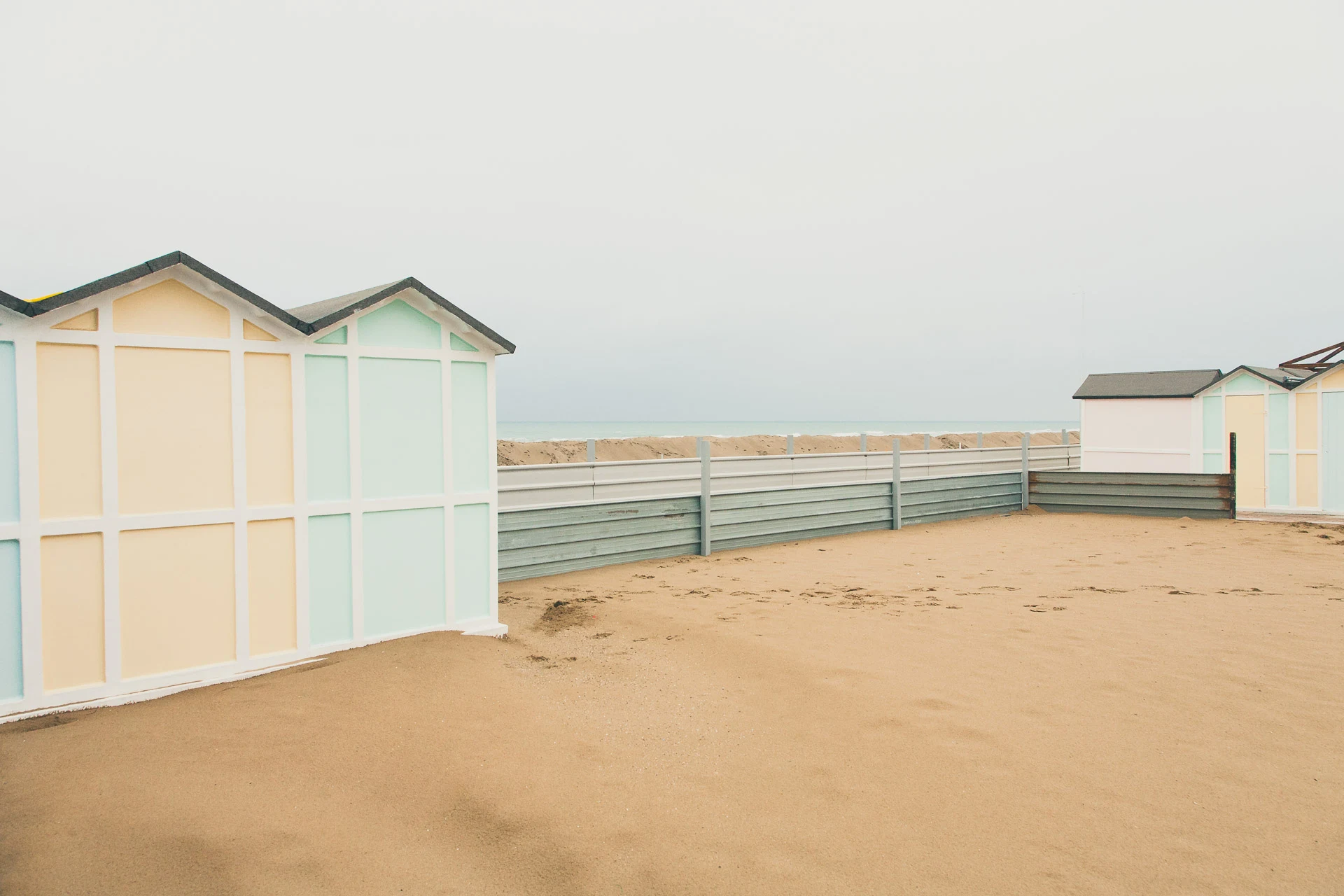 Pastel cabins beside an empty sandy beach