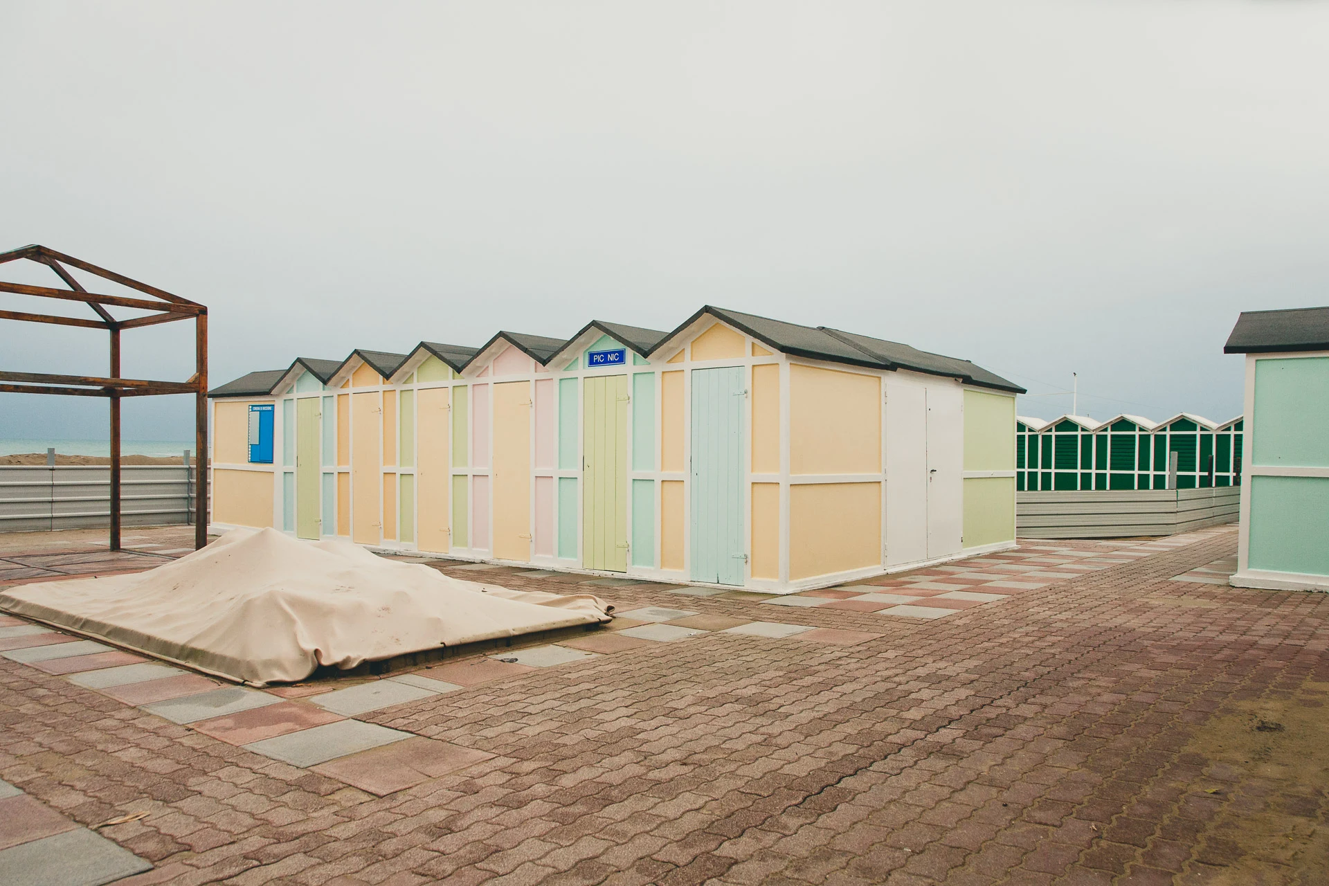 Pastel beach cabins on an empty paved promenade