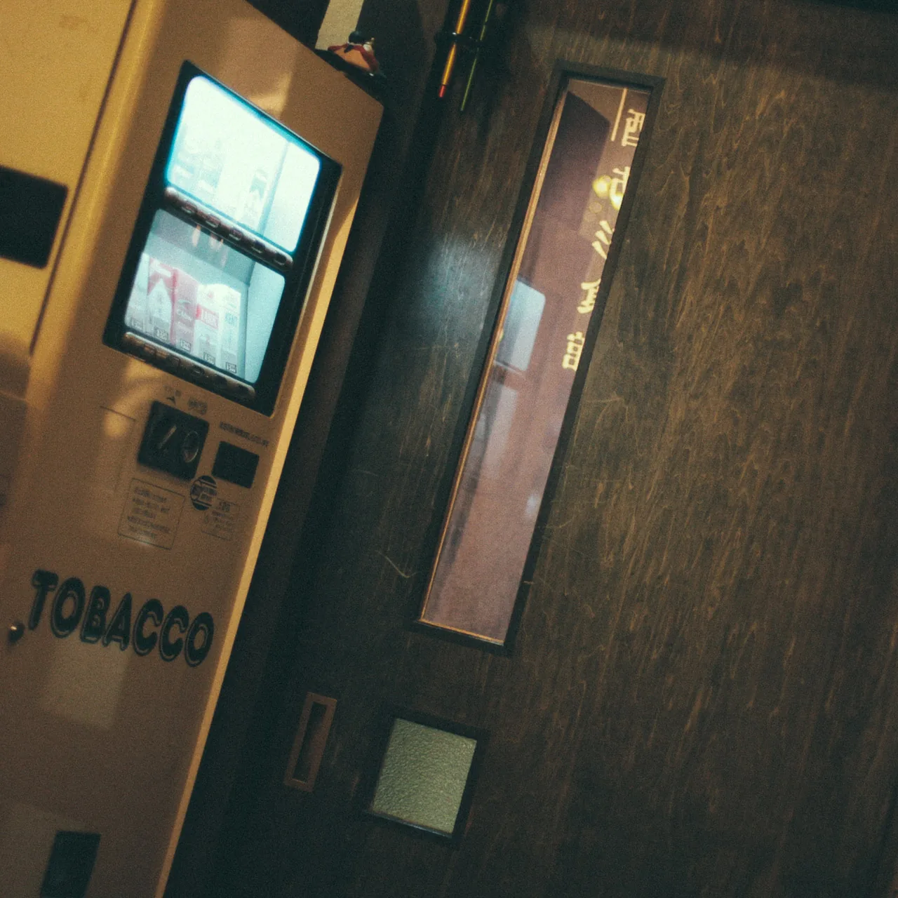 A cigarette vending machine by a wooden door