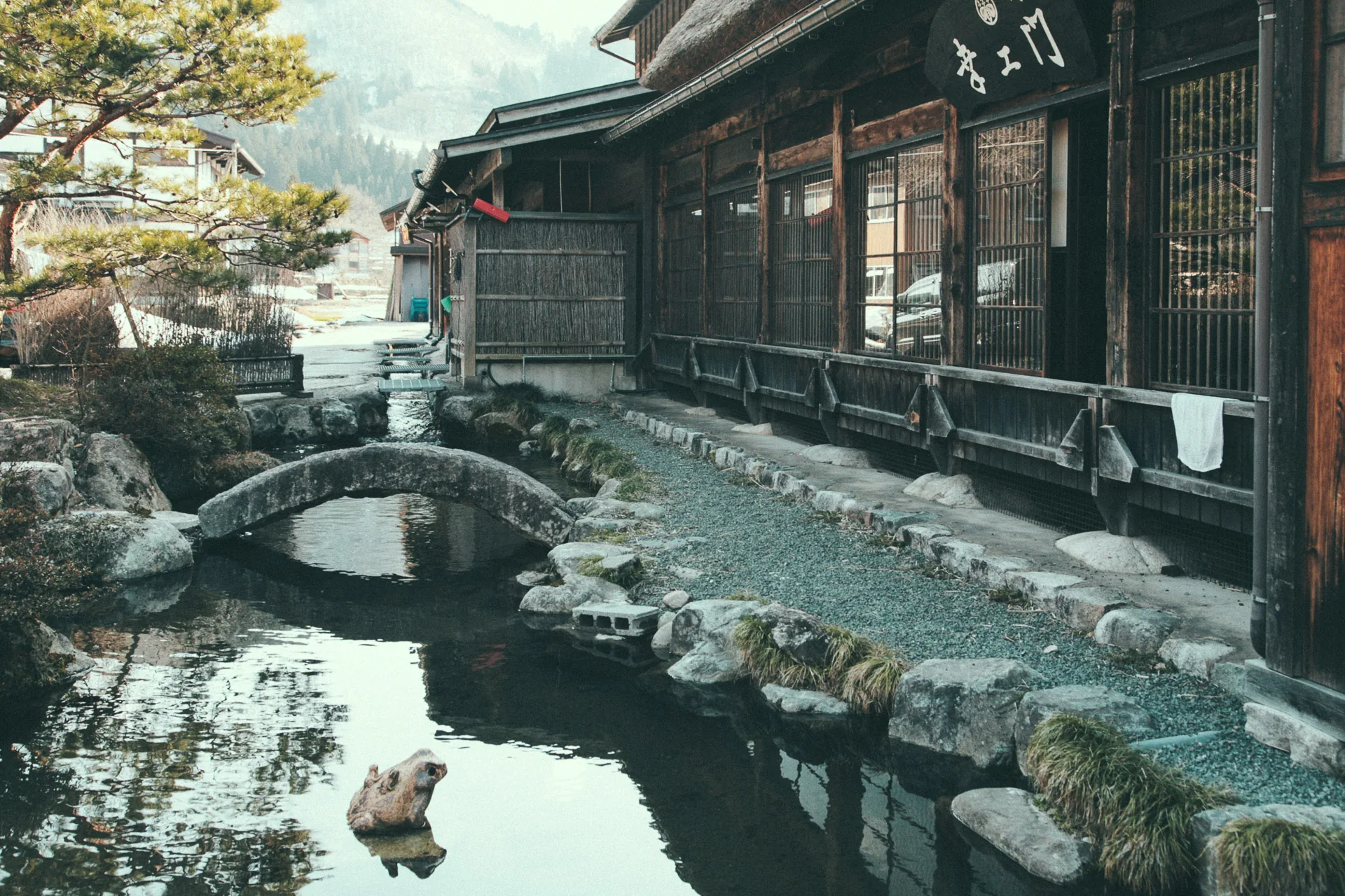 A stone bridge over a stream beside a temple