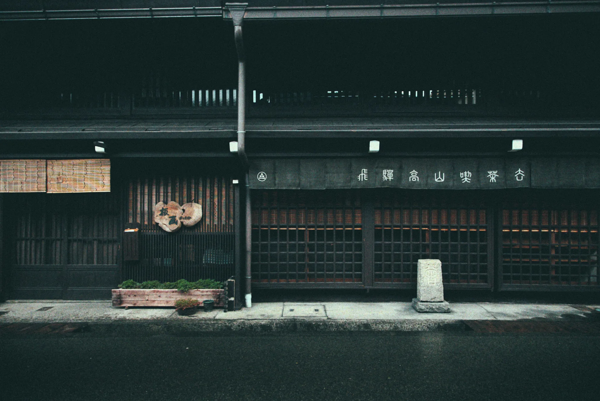 A long dark wooden facade with a small stone marker
